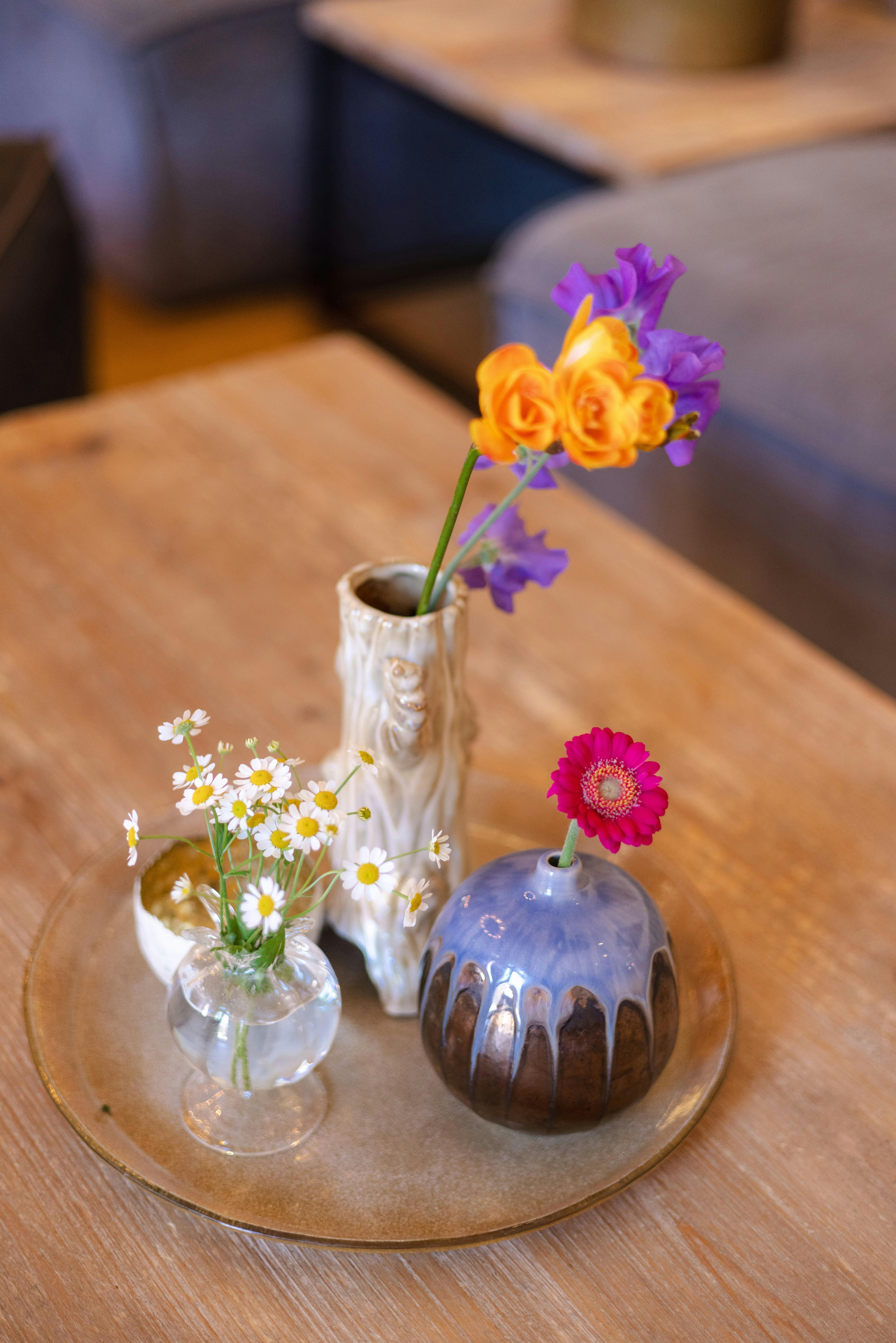 Mixed ceramic bud vases on brass tray on wood table